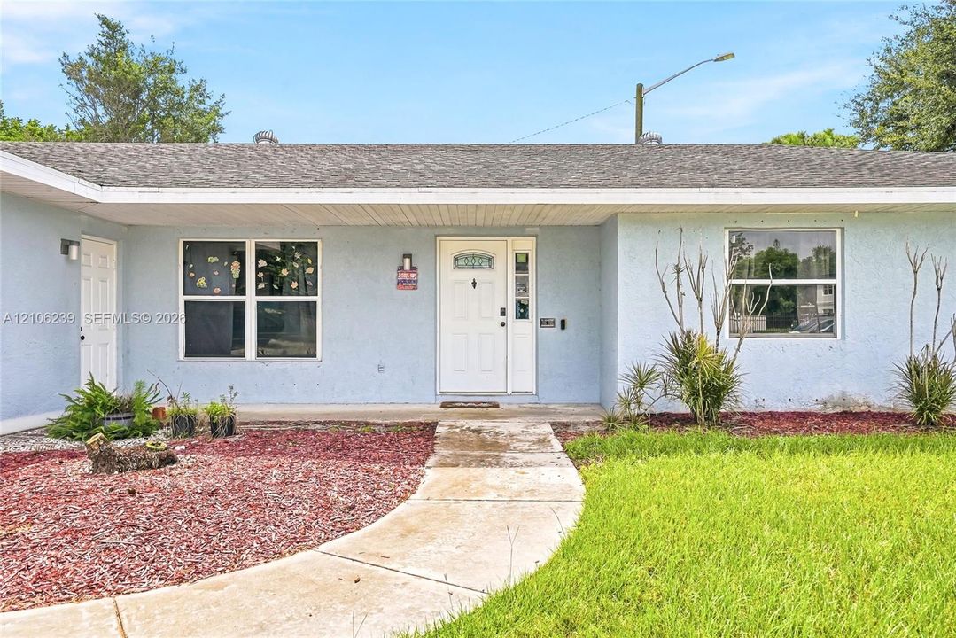 Single-story residence featuring a light-toned stucco exterior, asphalt shingle roofing, and a front entry door with a decorative glass insert