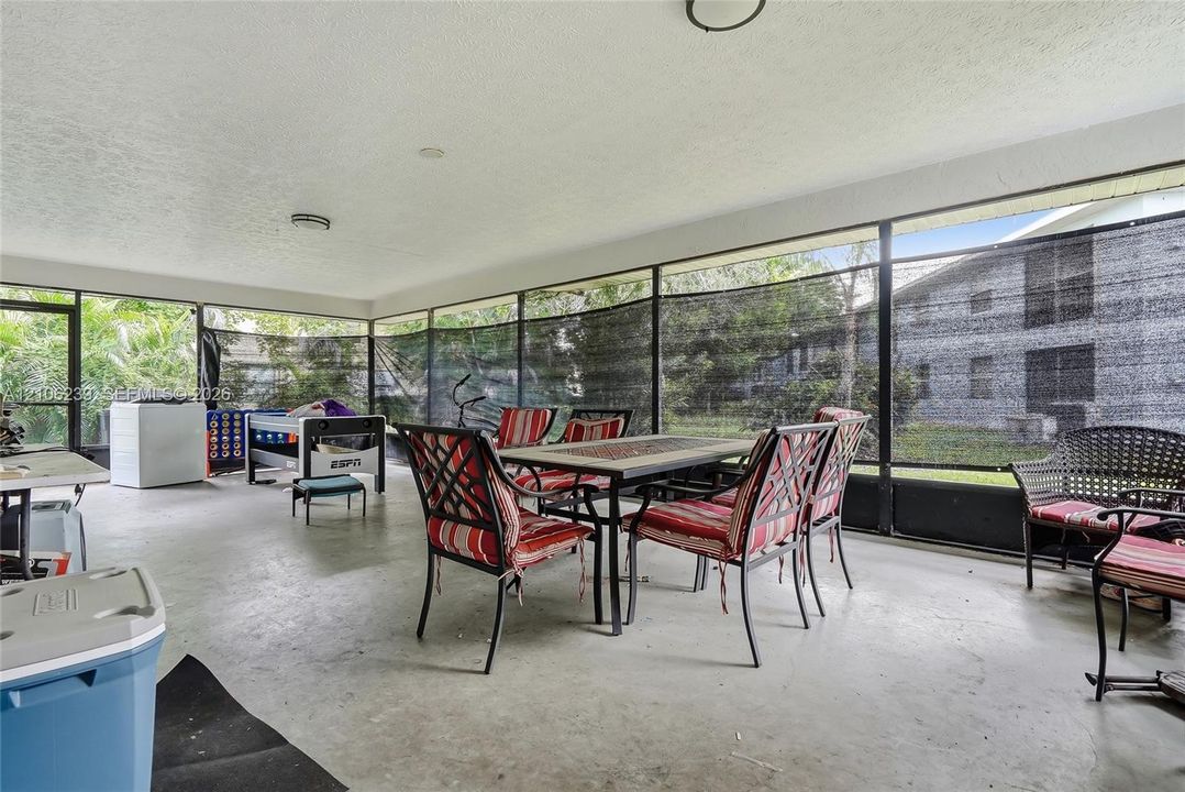 Screened-in patio featuring concrete flooring, ceiling-mounted lighting, and expansive mesh screening