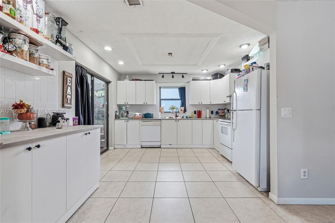 Kitchen featuring white cabinetry, tile flooring, recessed lighting, and sliding glass doors