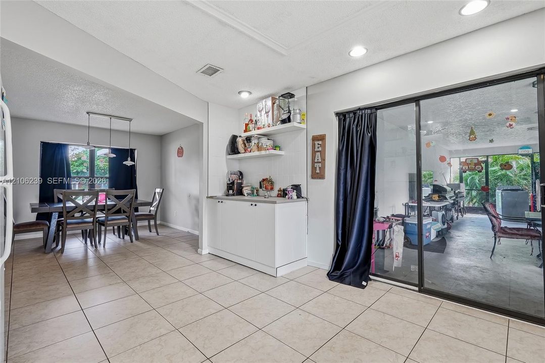 Ceramic tile flooring, built-in lower cabinetry with countertop, floating shelving, recessed lighting, and sliding glass doors
