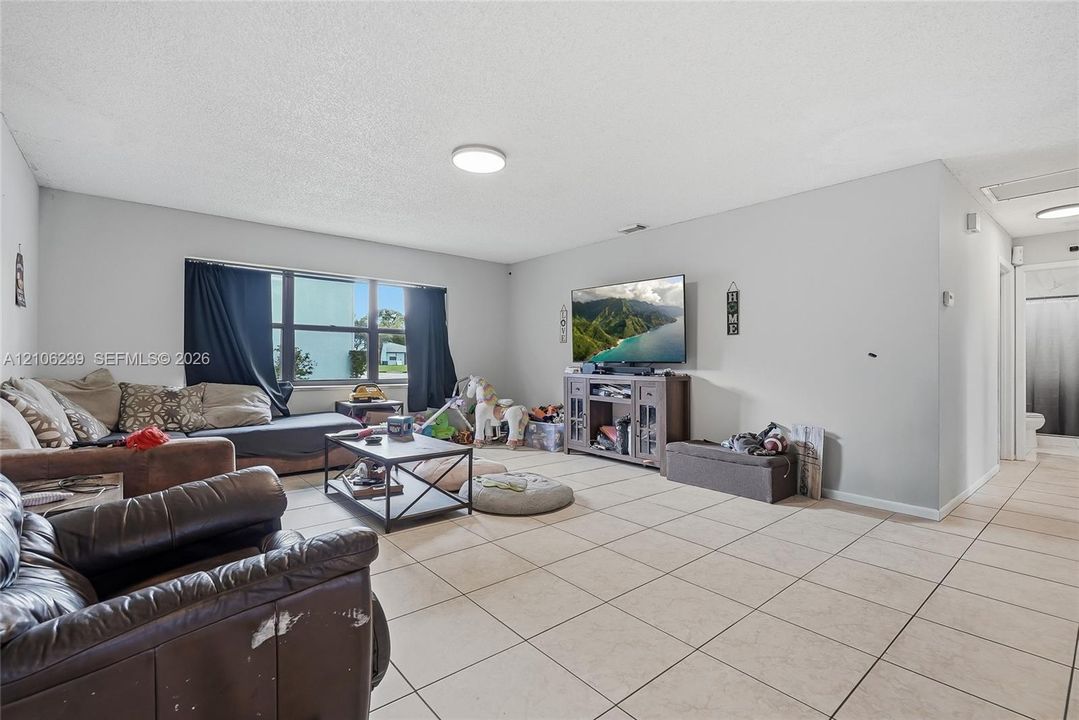Neutral-toned interior space featuring tile flooring, a large window, and recessed ceiling lighting