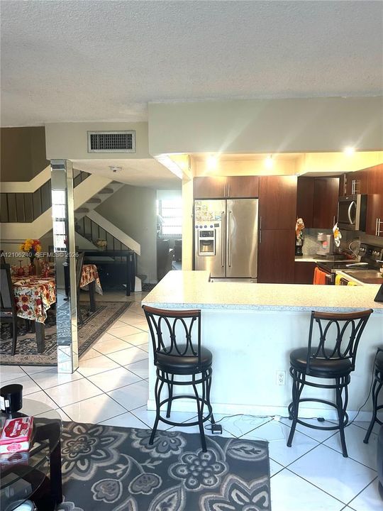 Kitchen featuring dark wood-finish cabinetry, stainless steel appliances, speckled stone-composite countertops, a dual-basin stainless steel sink, and track lighting