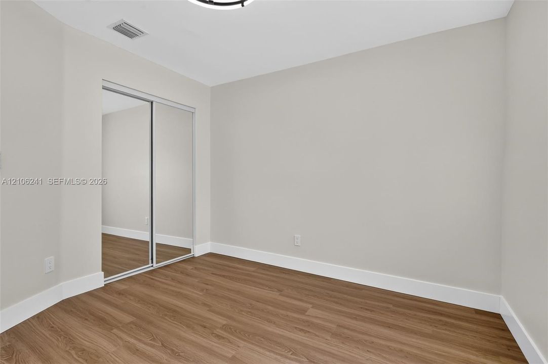 Interior space featuring wood-finish flooring, neutral wall paint, and closet with sliding mirrored doors