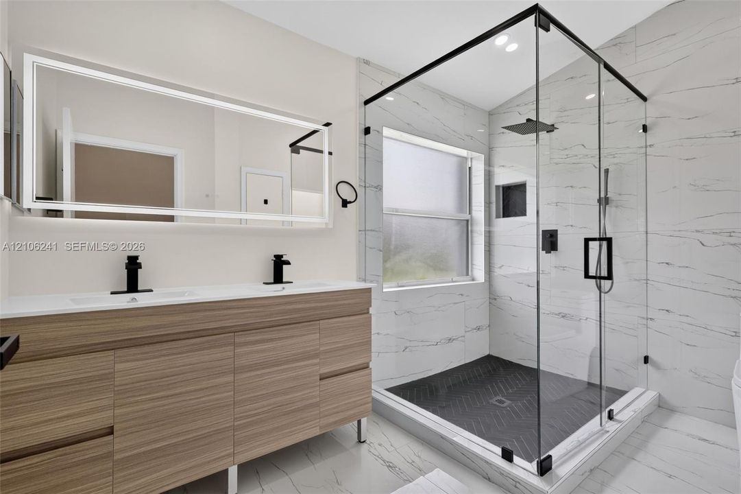 Double vanity with wood-finish cabinetry and quartz countertop, complemented by a large integrated LED-backlit mirror