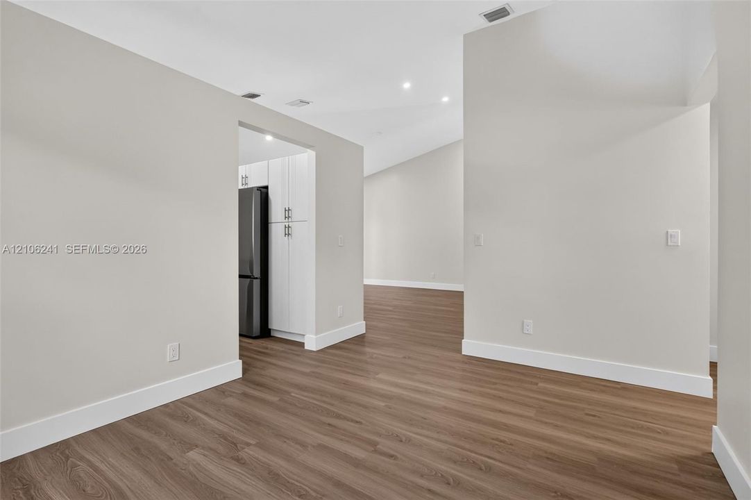 Vaulted ceilings, wood-finish flooring, recessed lighting, and white cabinetry