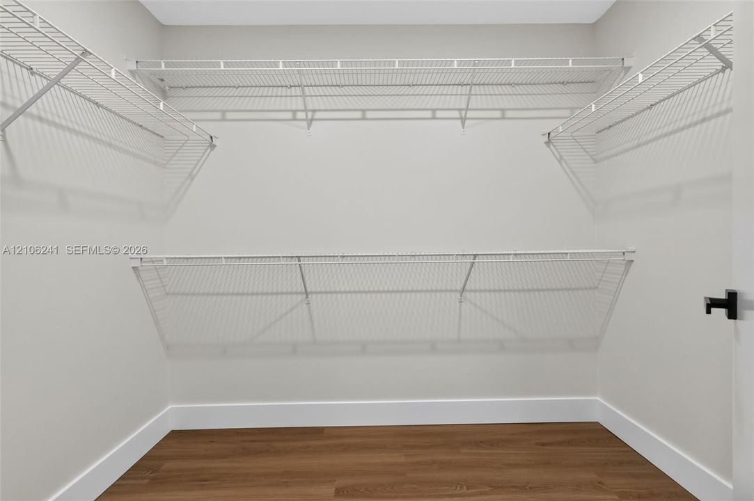 Walk-in closet featuring tiered wire shelving and wood-finish flooring