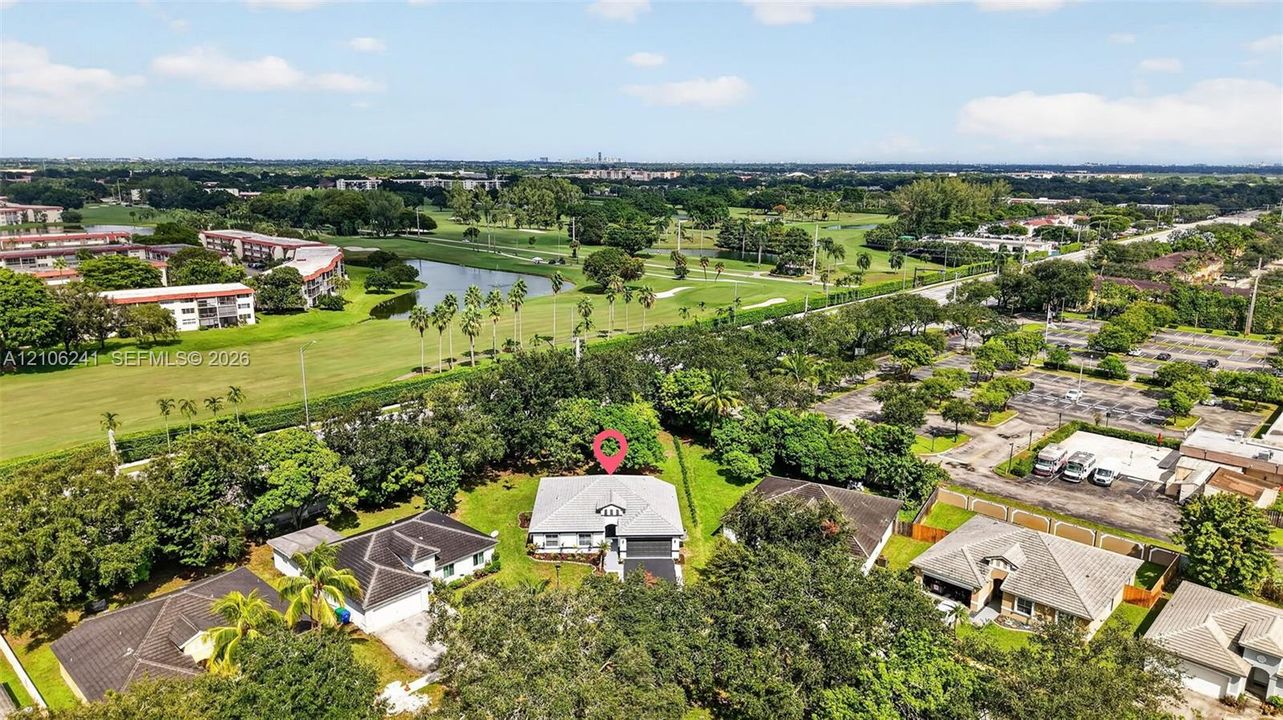 Aerial perspective of single-story residence featuring a hipped roof, attached garage, mature landscaping, and an expansive lot