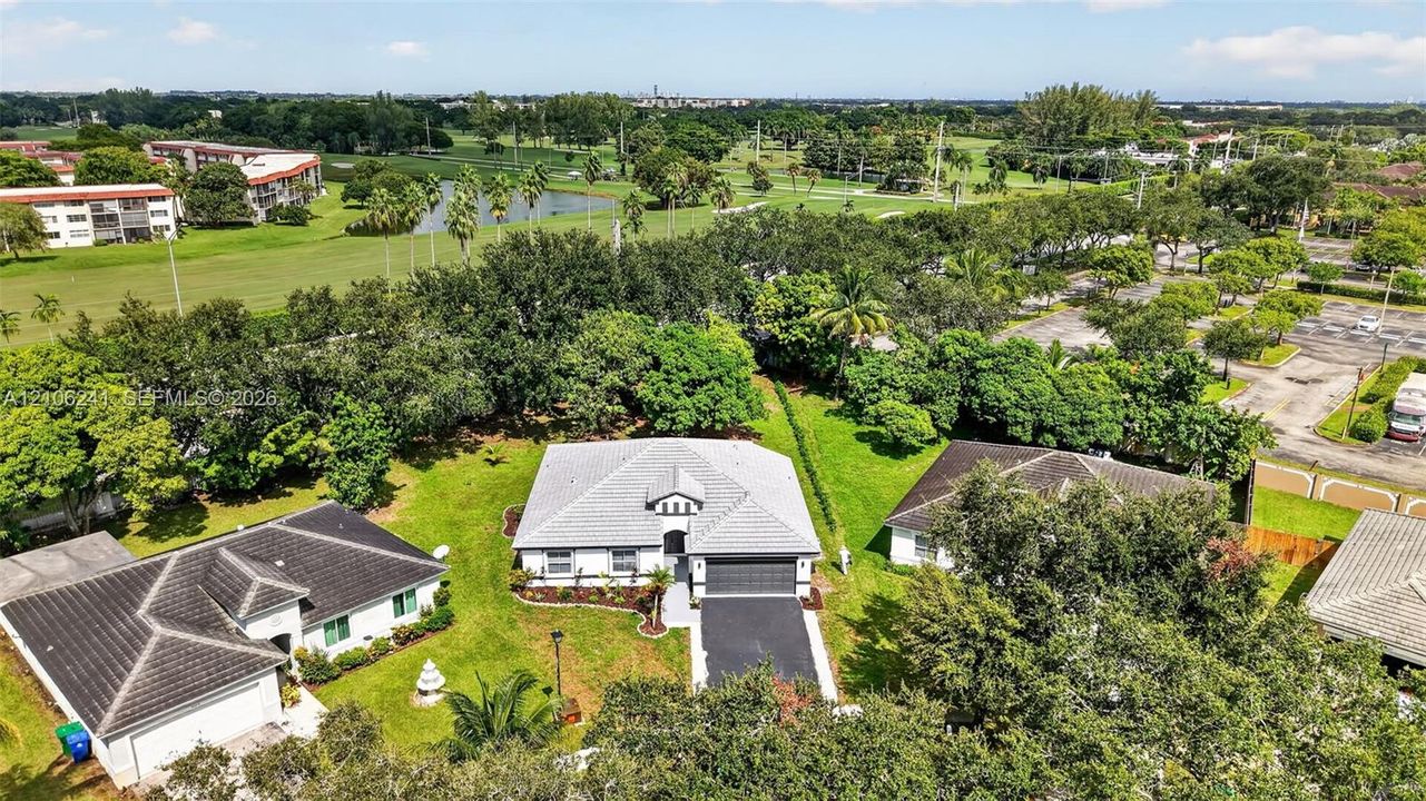 Single-story residence featuring a tile roof, light-toned exterior finish, attached two-car garage, asphalt driveway, and expansive lawn area