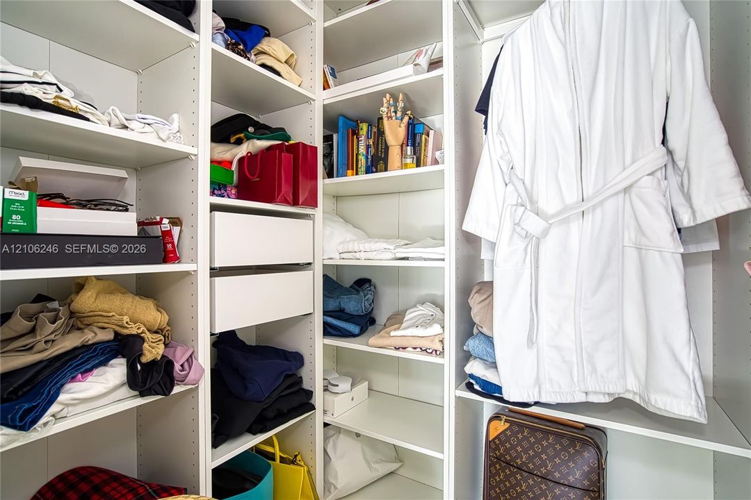 Customized walk-in closet featuring floor-to-ceiling white shelving, integrated adjustable storage cubbies, and dual soft-close drawers