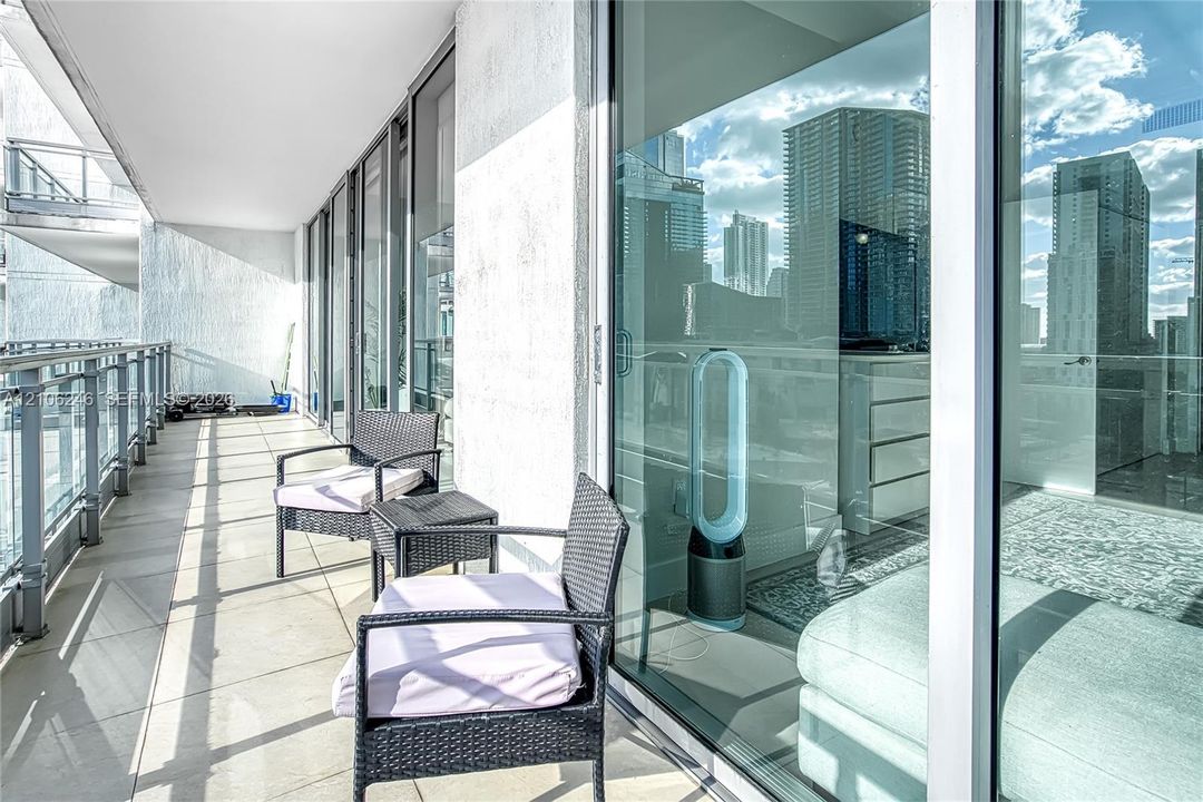 Covered balcony featuring tile flooring and a glass-paneled railing