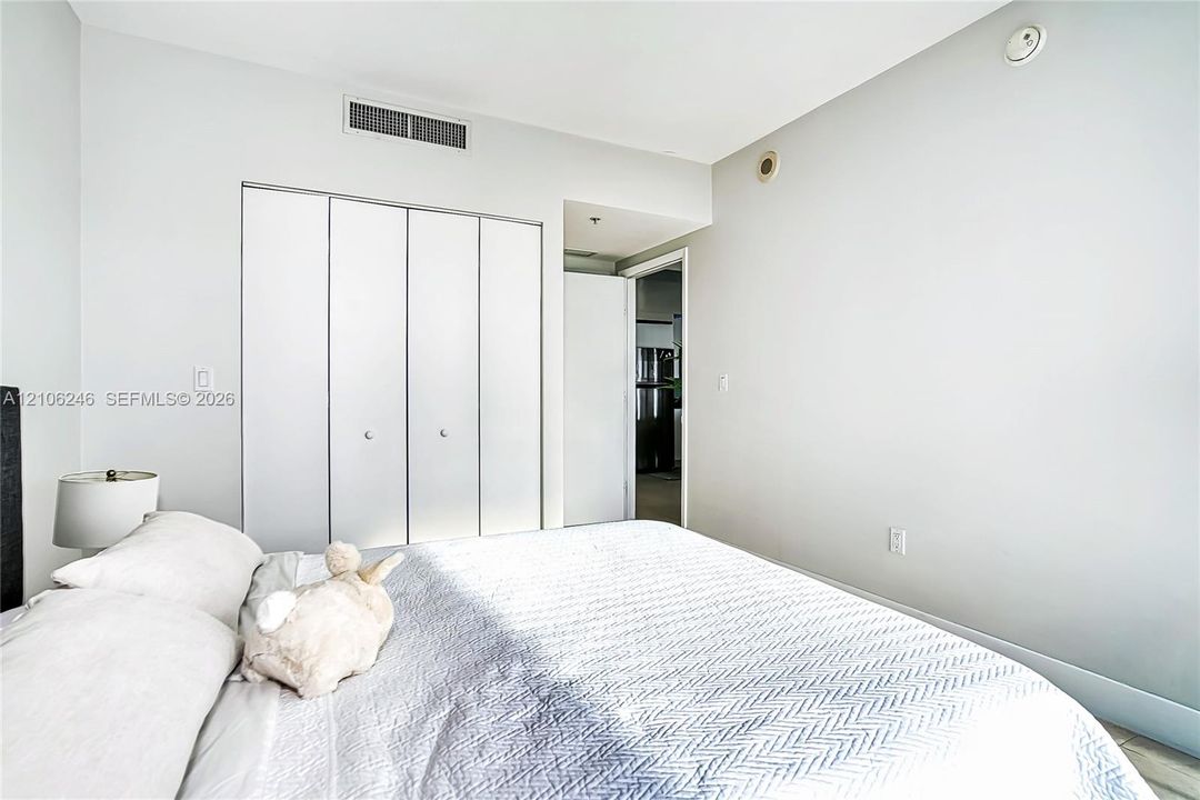 Neutral-toned room featuring a four-panel bi-fold closet with brushed metal hardware and light-toned flooring