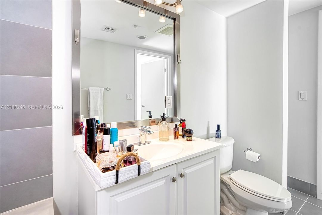 Bathroom vanity featuring a solid-surface countertop, integrated basin, brushed metal faucet, and framed rectangular mirror with integrated lighting