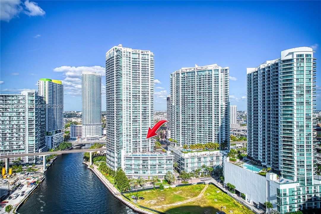 High-rise glass and concrete residential tower featuring private balconies, multi-story podium architecture, and waterfront positioning