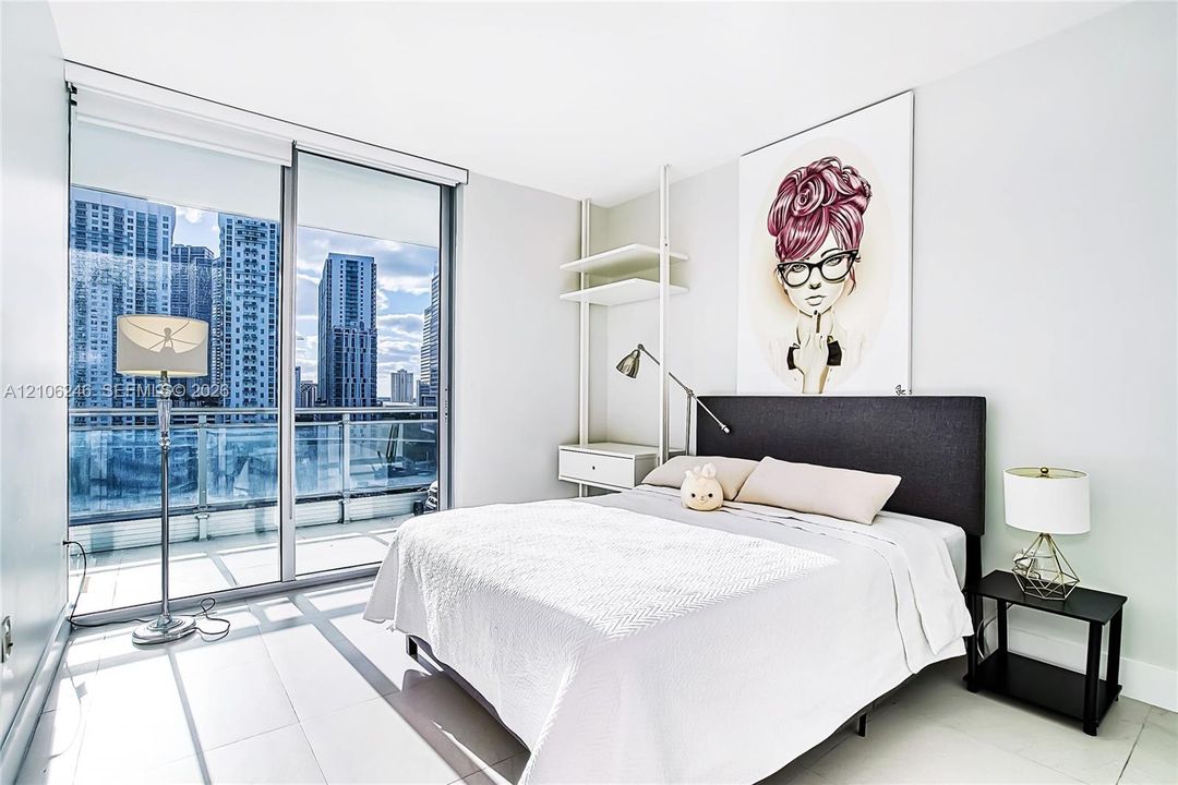 Floor-to-ceiling glass sliding doors, private balcony with glass railing, large-format tile flooring, and custom built-in shelving unit