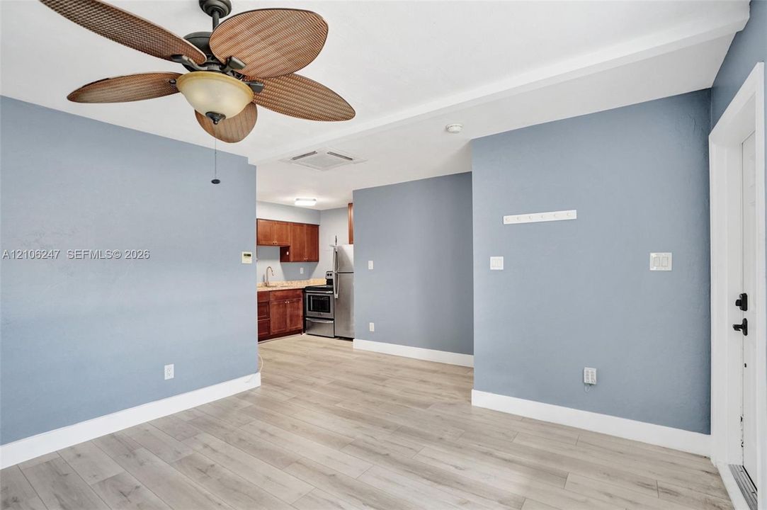 Bedroom interior featuring wood-finish flooring, a ceiling fan with integrated lighting, and a six-panel door