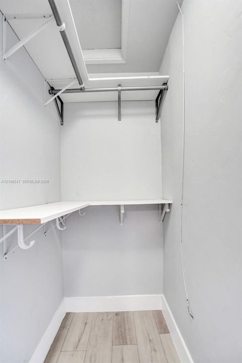 Wood-finish flooring, recessed ceiling-mounted HVAC unit, and palm-leaf style ceiling fan with central lighting