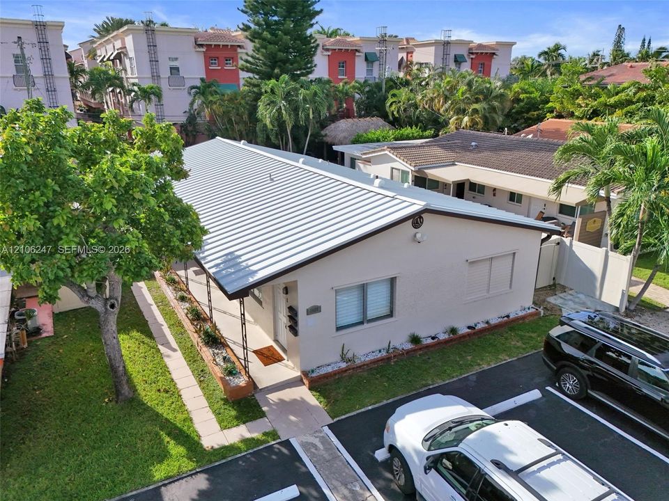 Single-story residence featuring a standing-seam metal roof, stucco exterior, covered front porch, and dedicated paved parking area