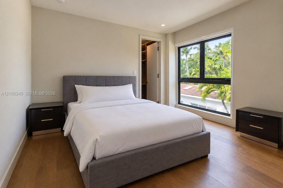 Room featuring wood-finish flooring, recessed lighting, a walk-in closet, and a large window with black framing