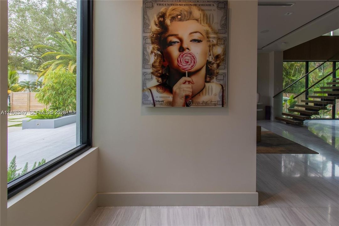 Floor-to-ceiling windows, polished stone flooring, and a floating wood-tread staircase with metal railing