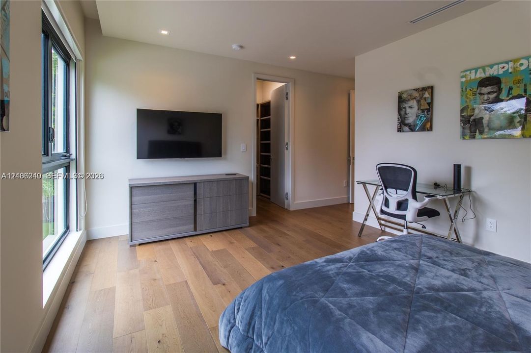 Wood-finish flooring, recessed lighting, large-format windows, and custom walk-in closet with built-in shelving