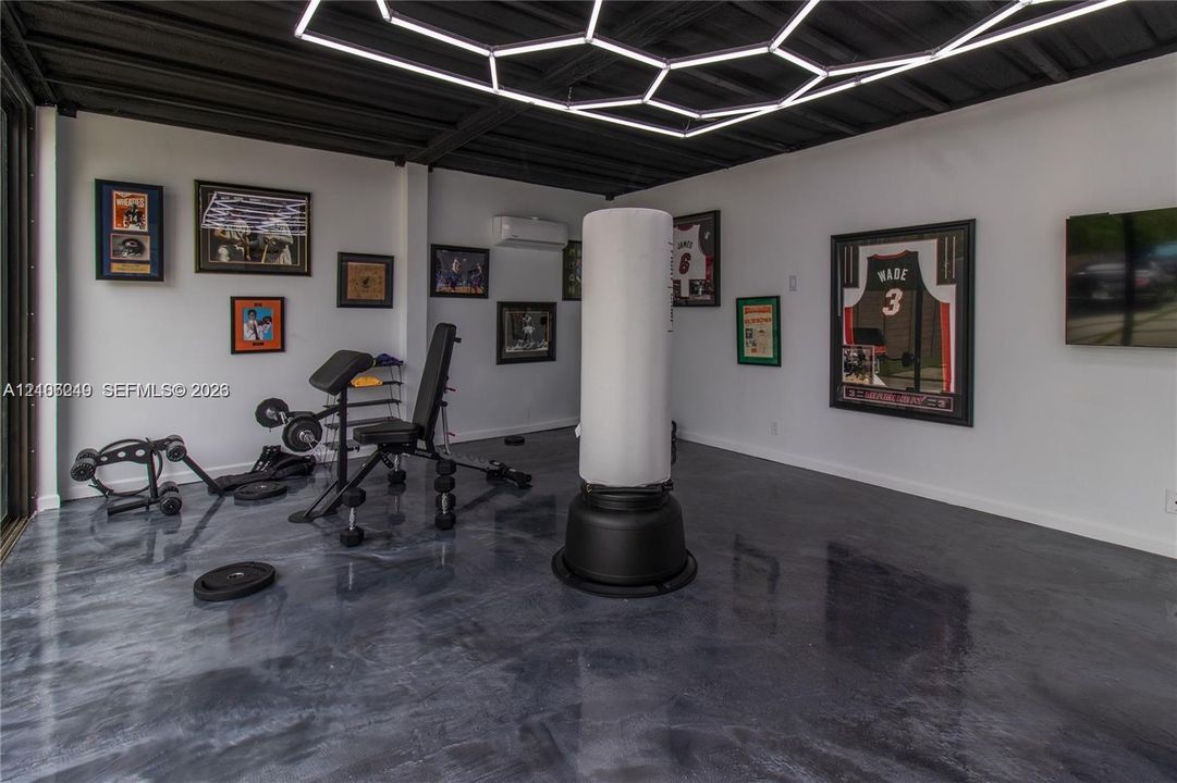 Polished concrete flooring, exposed ceiling beams, geometric LED overhead lighting, and wall-mounted climate control unit