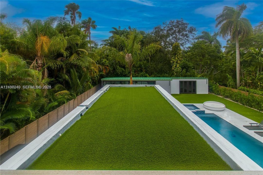 Backyard featuring a synthetic turf rooftop, swimming pool with integrated spa, paved terrace, and wood-paneled privacy fencing