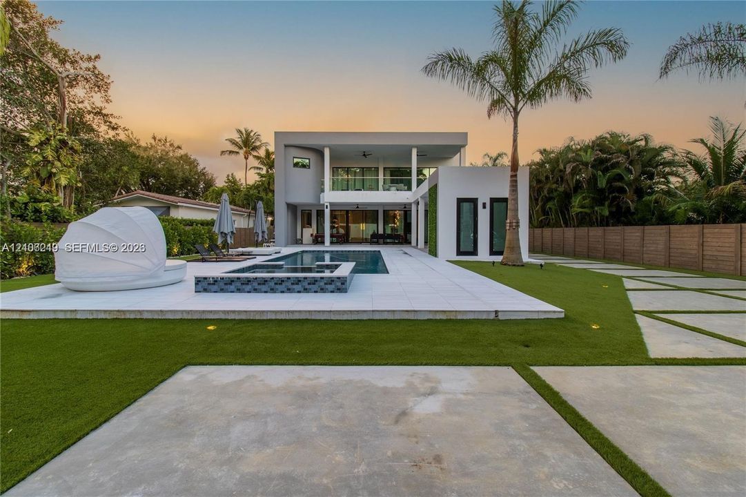 Modern exterior featuring a two-story flat roofline, integrated swimming pool with tiled spa, large-format porcelain patio pavers, and minimalist concrete hardscaping