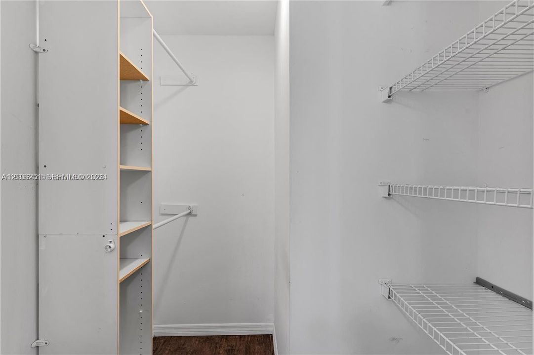 Walk-in closet featuring wood-finish flooring, built-in shelving unit, and multiple wire shelving tiers