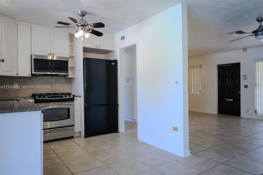 Kitchen featuring white cabinetry, stone-finish countertops, stainless steel gas range, built-in microwave, and tile flooring throughout