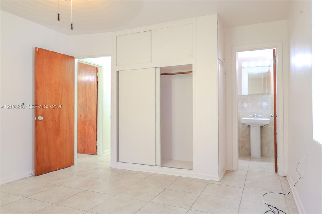 Ceramic tile flooring, built-in floor-to-ceiling closet with sliding doors, and solid wood-finish interior doors
