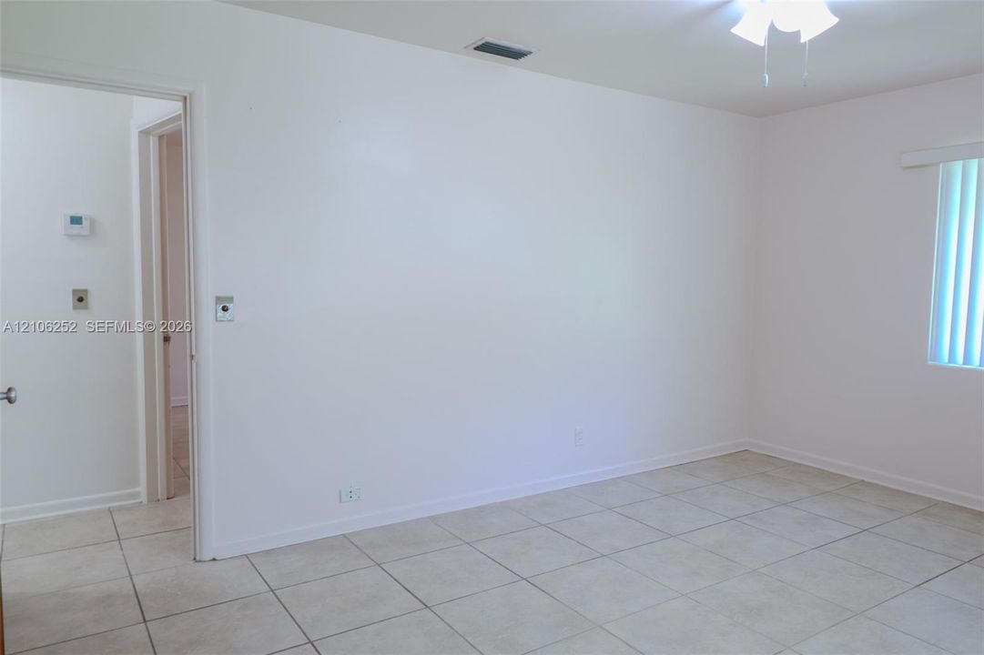 Neutral-toned ceramic tile flooring, ceiling-mounted light fixture with fan, and vertical window blinds