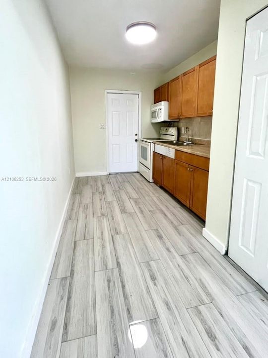 Kitchen featuring wood-finish cabinetry, neutral countertops, light-toned wood-finish flooring, and built-in appliances