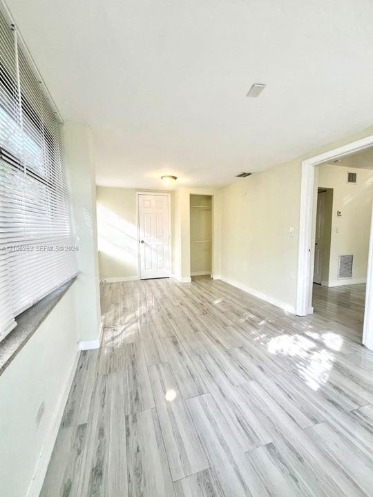 Master Bedroom featuring porcelin wood-finish flooring, white paneled interior door, built-in closet with shelving, and horizontal window blinds