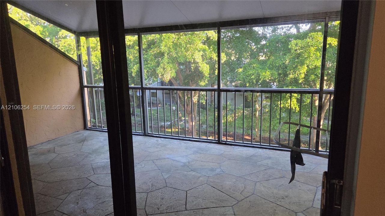 Screened porch featuring stone-paver flooring, metal railings, and a vaulted ceiling