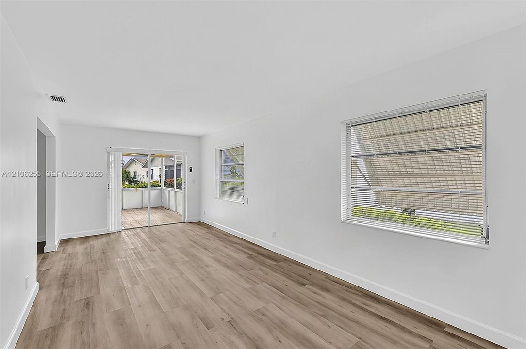 Neutral interior featuring wood-finish flooring, horizontal window blinds, and sliding glass doors