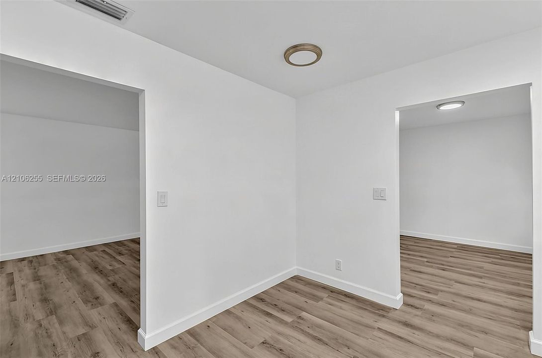 Neutral interior featuring wood-finish flooring, white walls, and flush-mount ceiling lighting