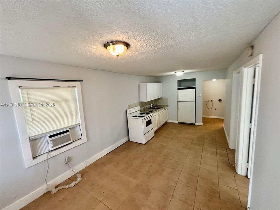 Kitchen featuring ceramic tile flooring, white cabinetry, a white freestanding range, and an integrated refrigerator