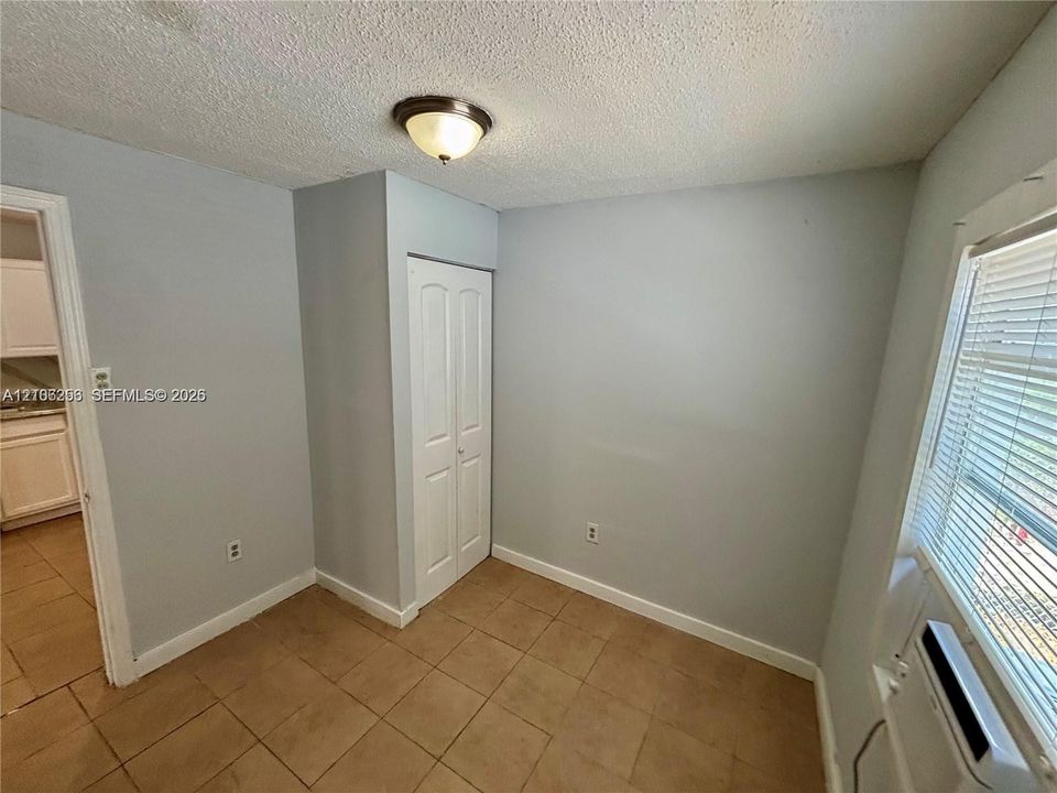 Room featuring ceramic tile flooring, a dual-panel closet door, and a flush-mount ceiling light fixture