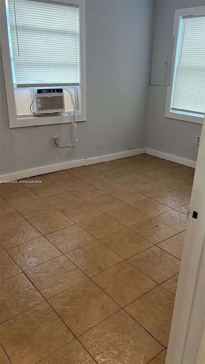 Neutral-toned interior space featuring large-format tile flooring and two windows with horizontal blinds