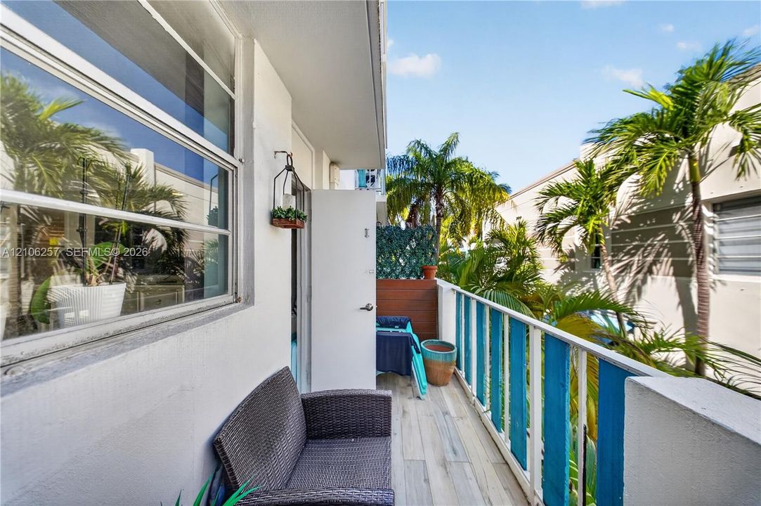 Rear Balcony featuring wood-finish flooring, metal railing, and a wall-mounted light fixture