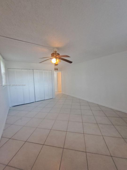Neutral tile flooring, ceiling fan with light fixture, and dual-panel closet doors