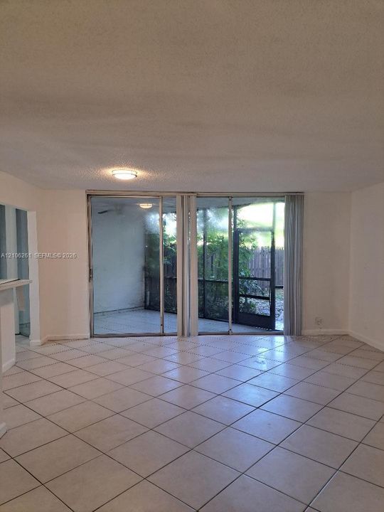 Open interior featuring large-format diagonal tile flooring, dual sliding glass doors, and a screened-in exterior enclosure