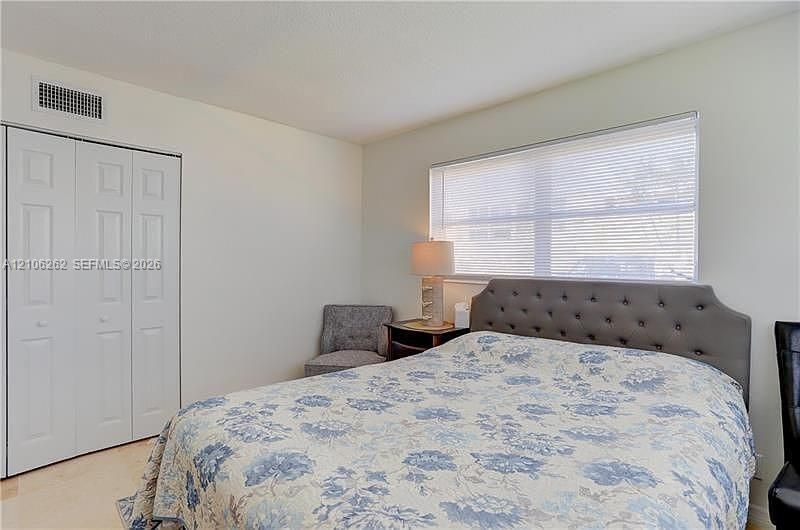 Room featuring neutral wall paint, a large horizontal window with fitted blinds, and a built-in closet with paneled double doors