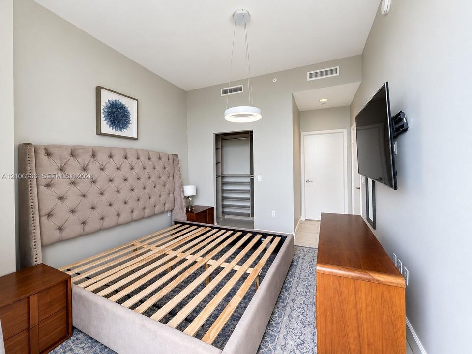 Room featuring high ceilings, circular LED pendant lighting, neutral wall paint, and an open walk-in closet with built-in shelving