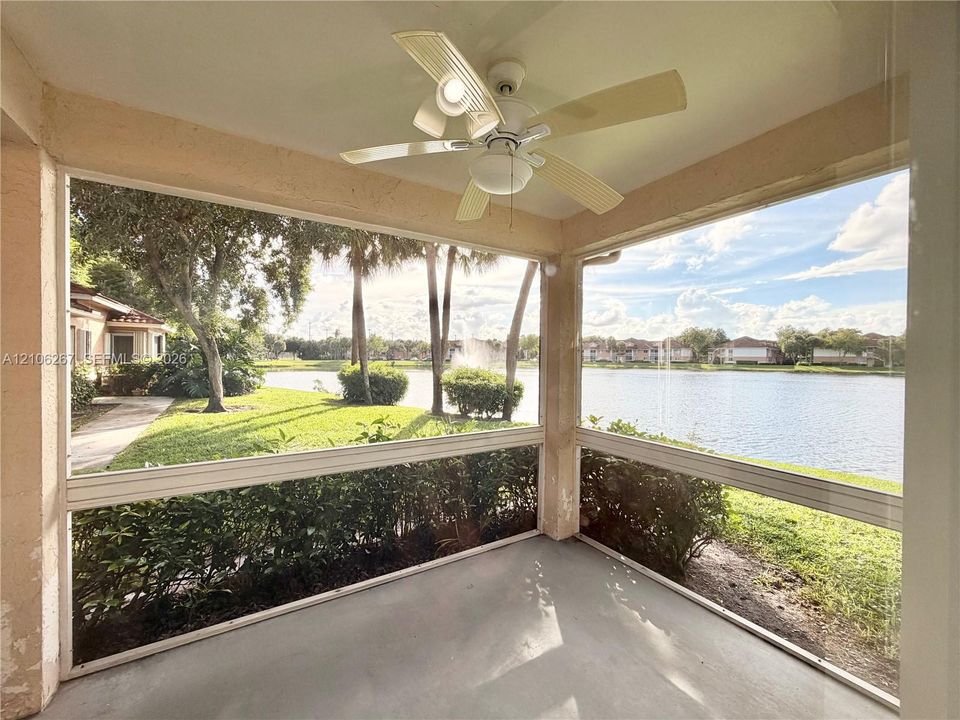 Screened-in patio featuring a ceiling fan with integrated lighting, concrete flooring, and water frontage
