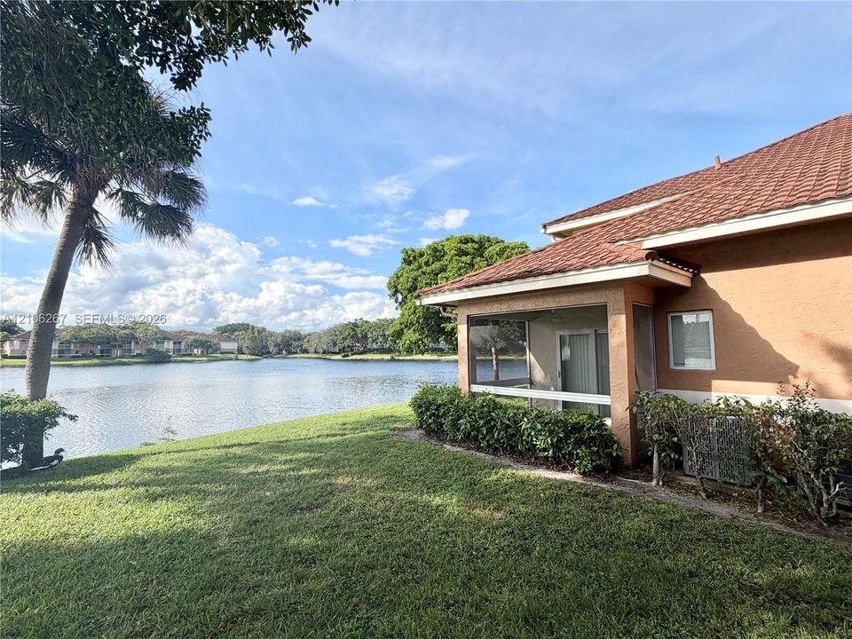 Screened lanai featuring tile roofing, stucco exterior, and direct water frontage on a natural lake
