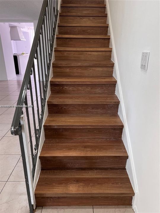 Staircase featuring wood-finish treads and a decorative metal railing
