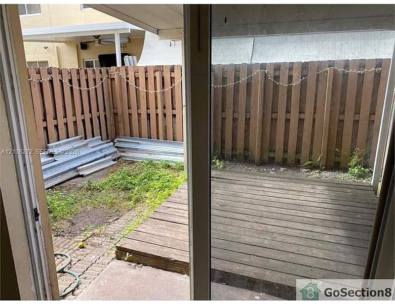 Private outdoor patio featuring a wood-plank deck, concrete paver accents, and a perimeter wood-slat privacy fence