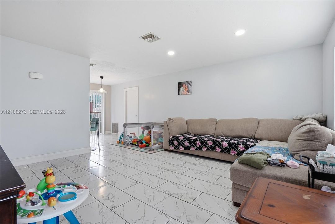 Open-concept living space featuring large-format rectified tile flooring with a marble-style finish and recessed ceiling lighting