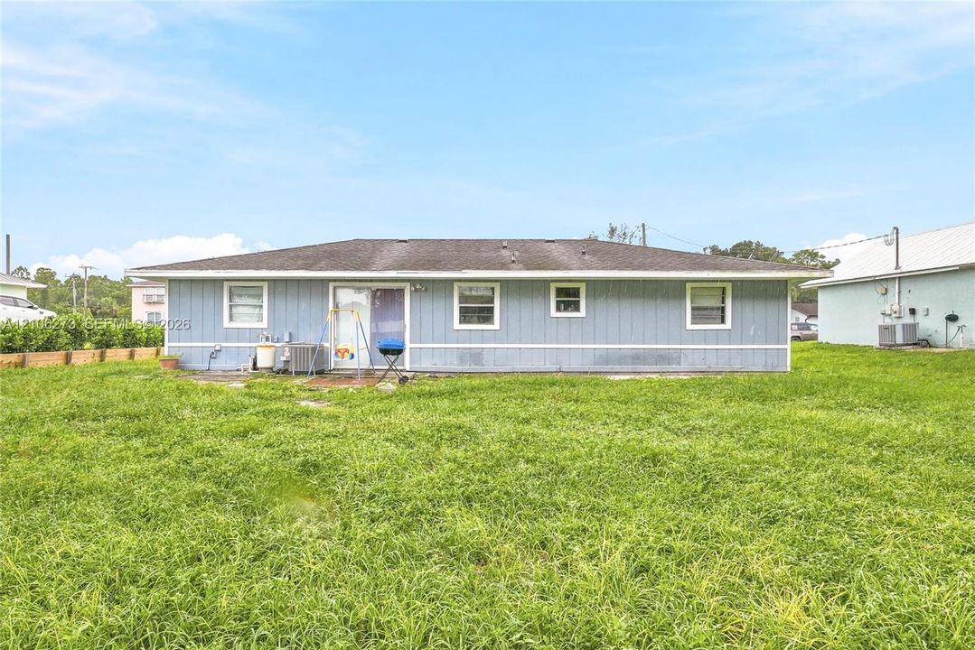 Single-story exterior with light blue horizontal siding, hipped roofline, and rear sliding glass door access